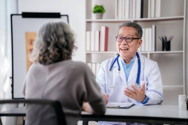 Erkek doktor hastane sağlık kontrolünden sonra ilaç kullanımını ve sağlık hizmetlerini anlatırken reçeteyi panoya yazıyor..