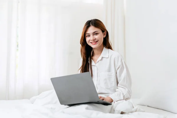 stock image Activity at home leisure lifestyle concept, Young woman in clothes casual watching the movie and typing to chatting with friends on laptop while sitting on comfy bed to leisure with lifestyle at home.