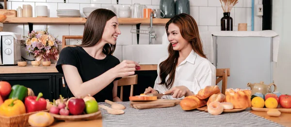 两名年轻女子在家里的现代厨房里 一边准备着健康的早餐餐 一边把果酱涂在面包上 一边享受着水果 — 图库照片
