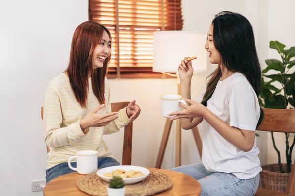 年轻的女同性恋者夫妇一边吃着零食 一边喝着热巧克力 一边聊着天 同时在家里的客厅里放松一下 — 图库照片