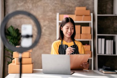 Küçük işletme paket teslimatı konsepti, panoya bilgi yazan kadın girişimci müşteriler için sevkiyat için ürün paketlerken ve çevrimiçi satış ticareti hakkında çalışırken.