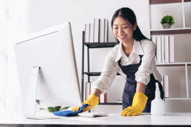 Önlüklü ev hanımı eldiven giyiyor. Evde çalışırken ve temizlik yaparken temizlik yapmak için mikrofiber kumaş kullanıyor..