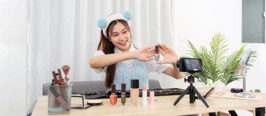 Genç güzellik uzmanı gülümsüyor ve kamera önünde videoyu paylaşırken tırnak cilası ürününü tavsiye ettiğini gösteriyor..