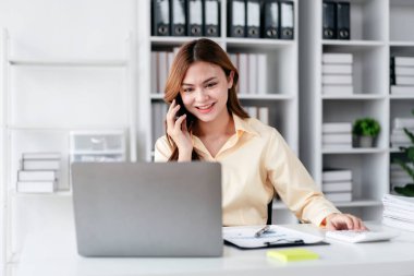 İş kadını çalışırken ve iş pazarlama planını okurken akıllı telefondan konuşuyor. Yatırımları analiz etmek ve ofisteki işletme projesini planlamak için rapor veriyor..