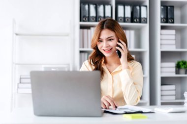 İş kadını çalışırken ve iş pazarlama planını okurken akıllı telefondan konuşuyor. Yatırımları analiz etmek ve ofisteki işletme projesini planlamak için rapor veriyor..