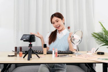 Genç Güzellik Etkilendirici, sosyal medyada veya stüdyoda web blogcusu paylaşımı için kameraya video kaydedilirken kullanım detaylarını tavsiye etmek ve açıklamak için makyaj fırçası gösteriyor.