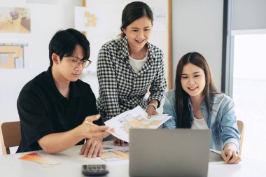 Mimarlık ekibi, modern ofisteki inşaat planları projesinde çalışırken planlar üzerine yeni bina tasarlamak ve çizmek hakkında birlikte beyin fırtınası yapmak için dizüstü bilgisayarda veri okuyorlar..