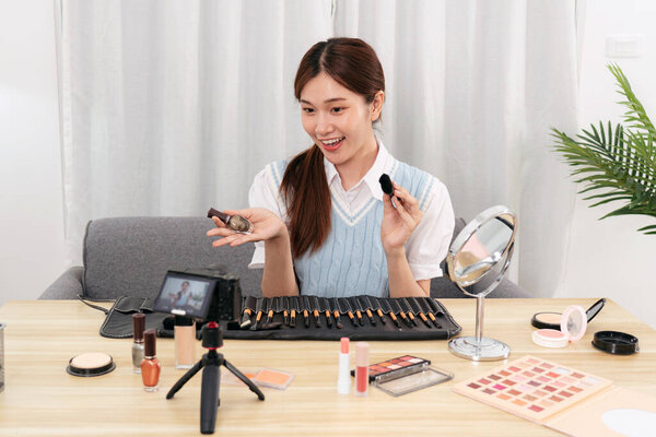 Молодой вдохновитель красоты показывает, чтобы рекомендовать косметическое оборудование и аксессуары для макияжа во время записи видео на камеру для обмена в социальных сетях или веб-блоггер в студии.