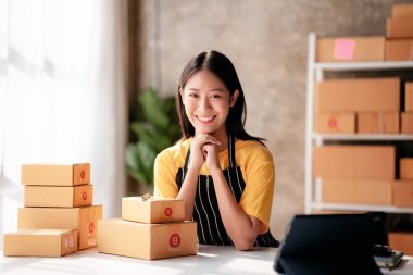 Küçük işletme paket teslimatı konsepti, kadın girişimci evde online satış işleriyle uğraşırken müşteriye teslimat için ürün paketliyor..