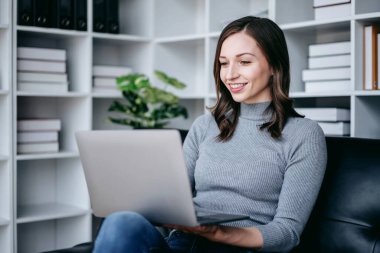 Teknoloji yaşam tarzı kavramına sahip bir iş kadını, iş kadını çalışırken kanepede oturup teknolojiyle rahatlarken dizüstü bilgisayarını film izlemek için kullanıyor..