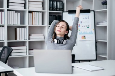 Teknoloji yaşam tarzı kavramına sahip iş kadını, iş kadını boynuna kulaklık takıyor ve işten sonra rahatlamak için kafasının arkasından el ele tutuşuyor..