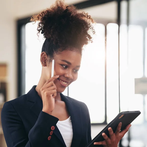 African american businesswoman in suit using tablet to reading accounting information of new business and thinking about strategy of project while standing to working in modern workspace.