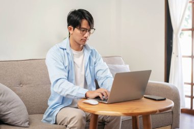 Gündelik iş adamı rahat bir koltukta oturup yeni iş için düşünceli bir fikirle evde iş projesi hakkında bilgi yazmak ve çalışmak için dizüstü bilgisayar kullanıyor..