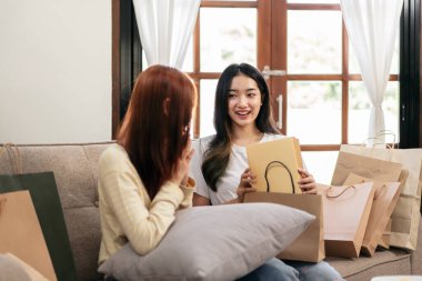 Genç bayan lezbiyen sürpriz bir yüz ifadesi ve kız arkadaşından hediye alırken aynı zamanda evdeki büyük rahat kanepede rahatlamak için birlikte vakit geçiriyorlar..