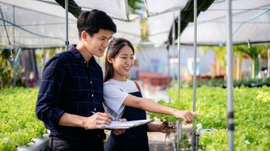 Bir adam ve bir kadın bir seradaki bitkiye bakıyorlar.