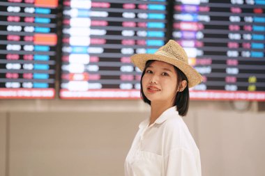 Hasır şapkalı bir kadın büyük bir vitrin tahtasının önünde duruyor. Gülümsüyor ve mutlu.