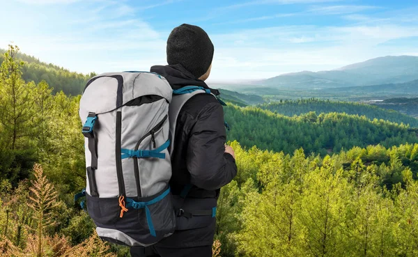 年轻人背着沉重的背包 在阳光灿烂的寒冷天气在山上徒步旅行或远足 独行或流浪的冒险概念 图库图片