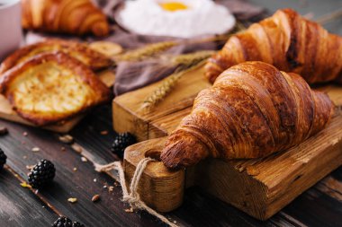 Board with tasty croissants and pastries on table