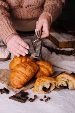 woman rubs chocolate on fresh baked croissants