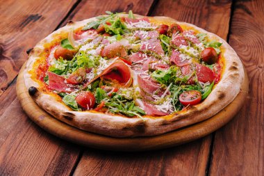 Pizza with prosciutto meat, cherry tomatoes, arugula and parmesan cheese