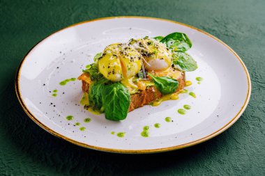 bread toast with avocado, poached egg, salmon and basil leaves