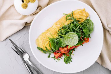 Omelet with arugula, tomatoes and basil in a plate