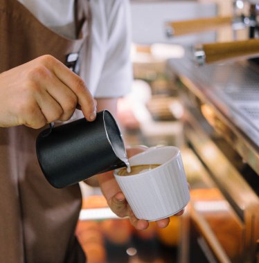 Barista kahveye süt döker.
