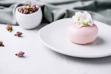 Pink mousse cake decorated with white flowers