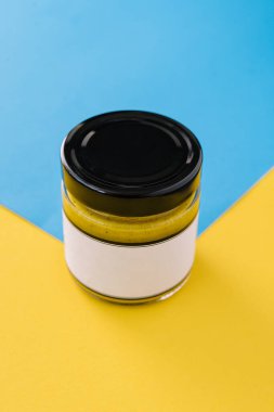 Bottle of curry sauce on blue with yellow background