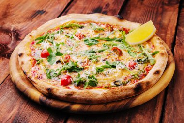 Pizza with arugula, cheese, yoghurt and cherry tomatoes closeup