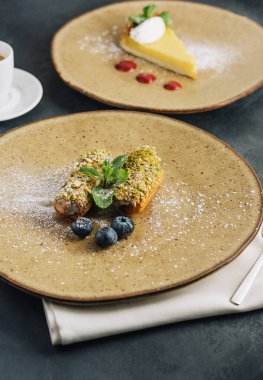 Tasty eclairs with pistachios and cheesecake on plates