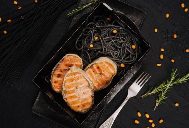 Italian salmon served over black spaghetti noodles