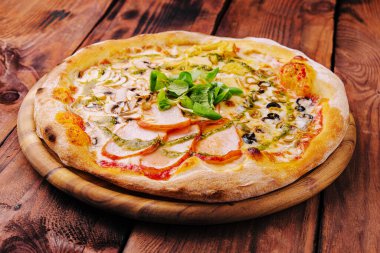 Pizza with ham and mushrooms on a wooden board