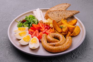 sausages with boiled eggs, tomatoes and potatoes with cheese