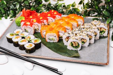 Büyük bir tabakta farklı suşi ruloları.