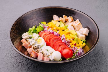 Bowl with chicken, egg, tomatoes, lettuce, corn, red onion and blue cheese