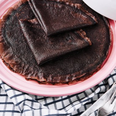 Chocolate pancake on pink plate close up