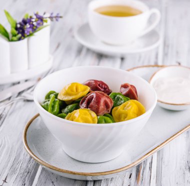 Cooked multi-colored tortellini dumplings close-up in a bowl
