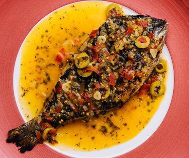 Dorado baked with special sauce on red plate
