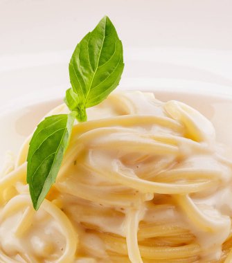 Spaghetti with white cream sauce on white plate