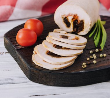 Dilimlenmiş köfte ve domatesler kesim tahtasının üzerinde.