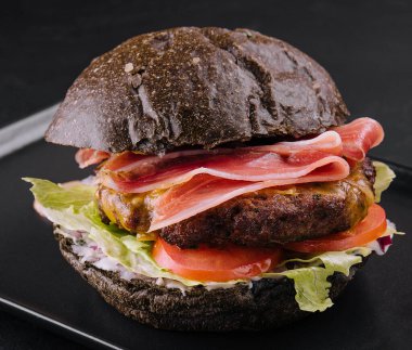 Modern black burger with prosciutto ham