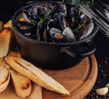Traditional barbecue italian blue mussel in wine sauce with baguette bread