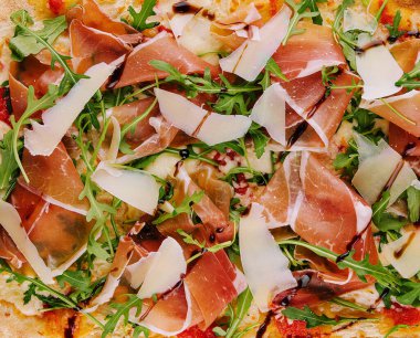Fresh pizza Parma made of parmesan, prosciutto ham and arugula