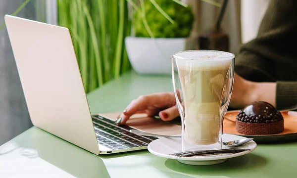 stock image Young woman using laptop with dessert and cup of coffee in cafe