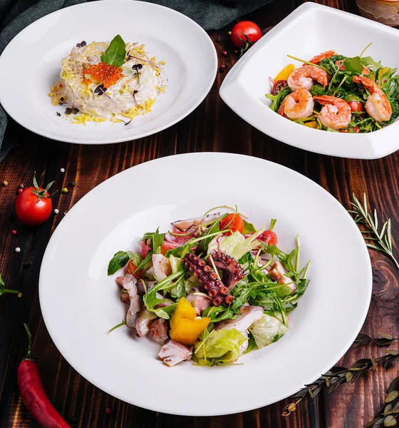 different salads in white plates on a wooden table