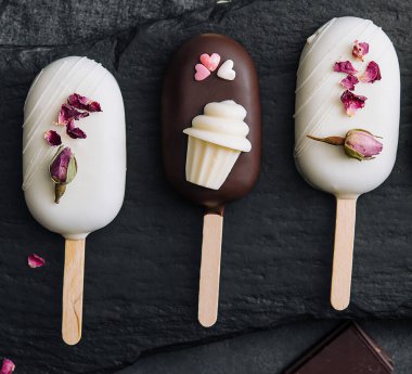 Top view of decorated cake pops ice creams on black background