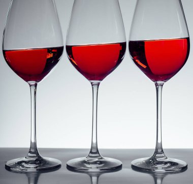 Gri arka planda üç kadeh şarap.