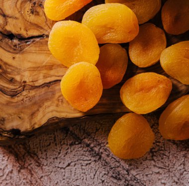 Tahtanın üzerinde kurumuş kayısı olan plastik bir kap.