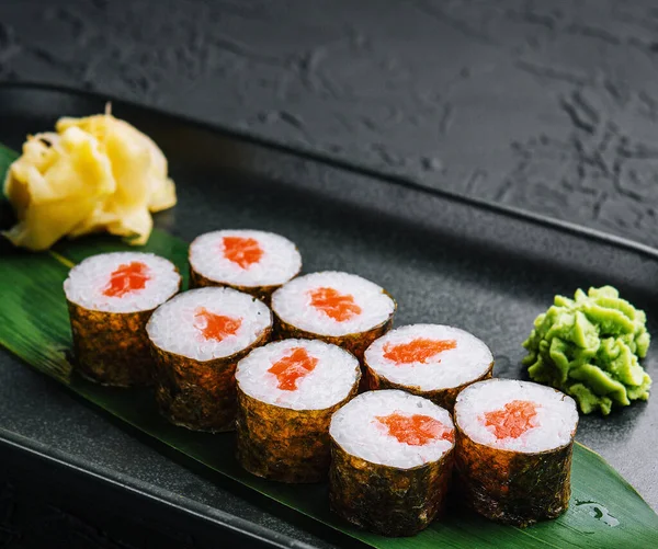 stock image Row of fresh maki sushi rolls on black plate